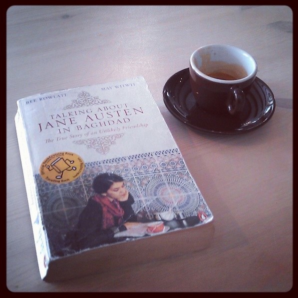 The book "Talking about Jane Austen i Baghdad" is on a table, a cup of coffee on the top right corner.