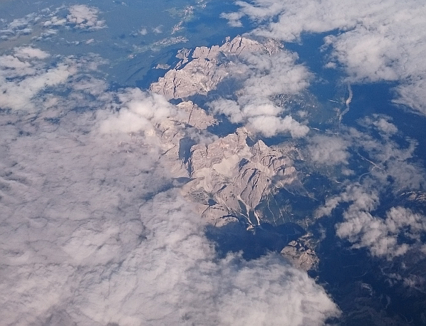 The Alps seen from above, covered by a few clouds.