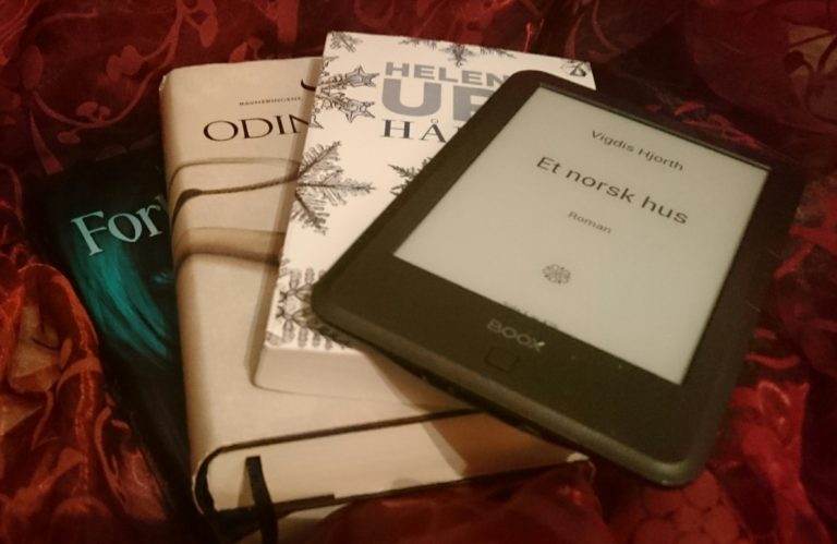 A pile of books on a red fabric. On top there's an ereader.