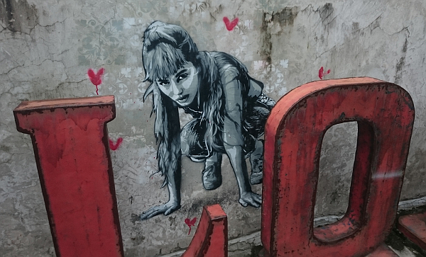 A streetart piece of a girl, with hearts around, by Quint.