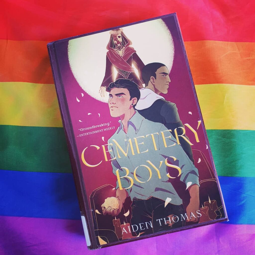 The book «Cemetery Boys» on top of a rainbow flag.