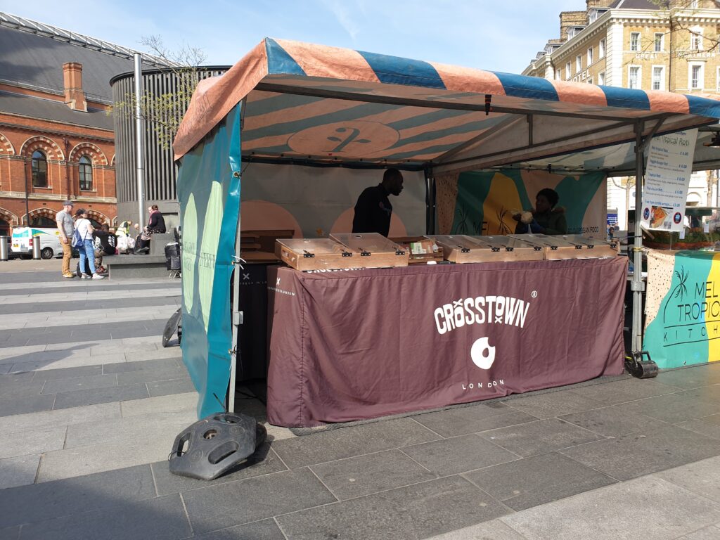 A food stall with wooden food displays with glass doors. On the front "Crosstown" is written.